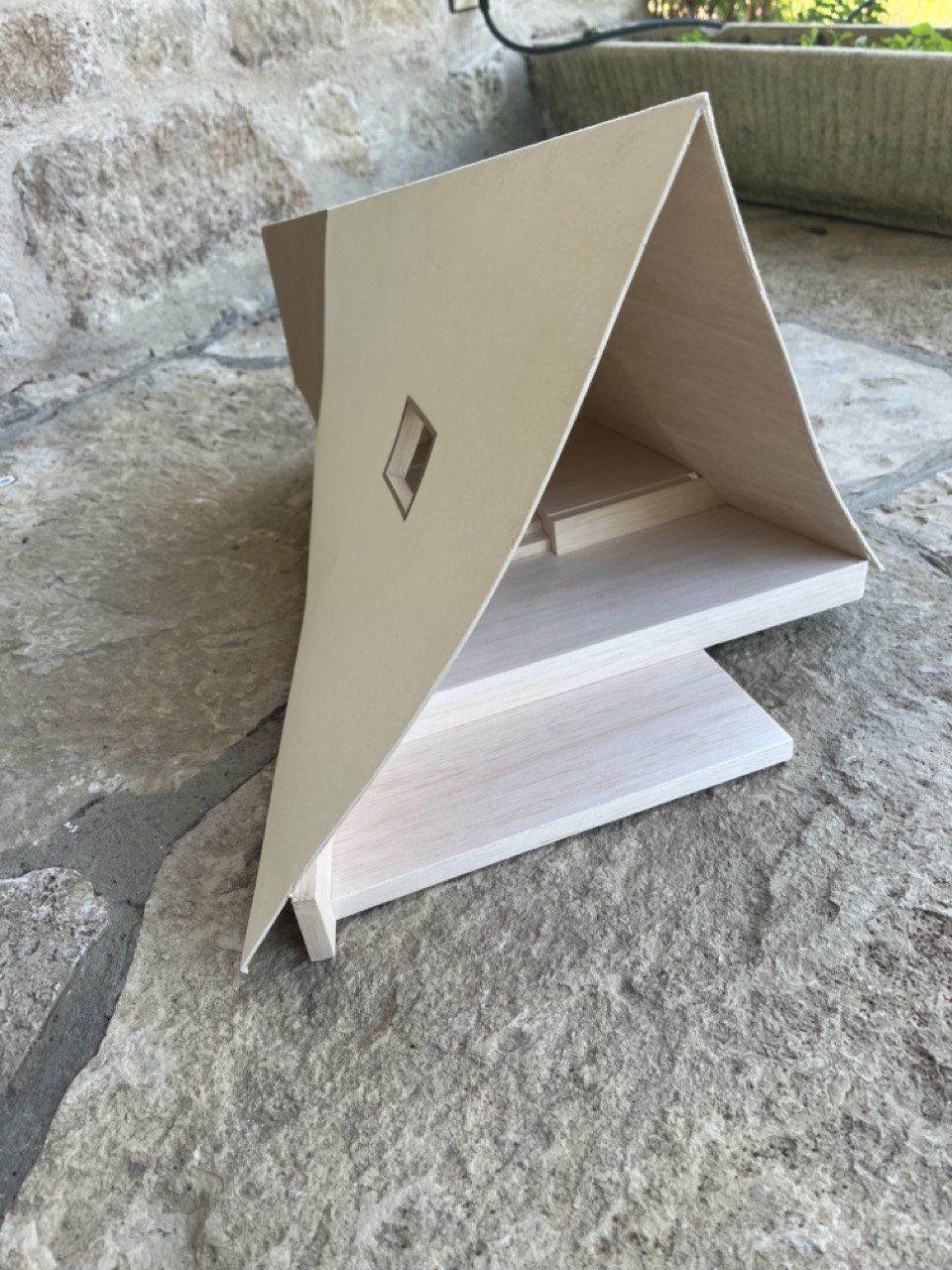 Maquette blanche d’un lodge en forme de A posée sur une pierre