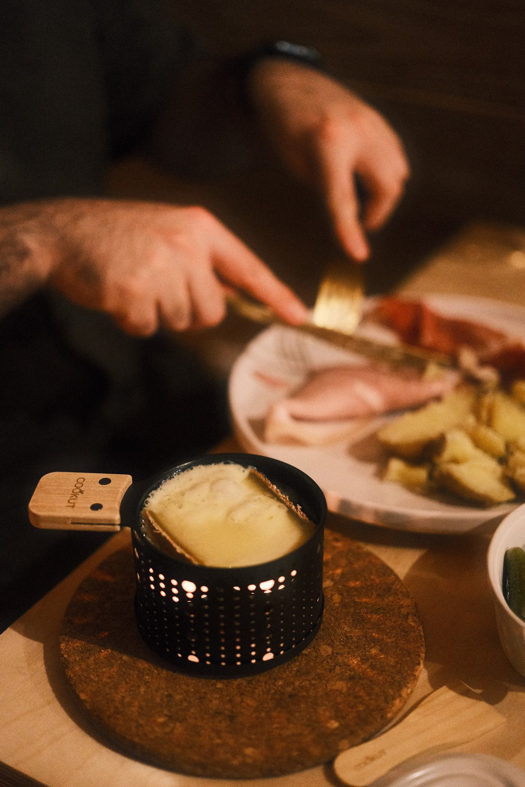 Raclette au fromage fondu servie avec charcuterie et pommes de terre