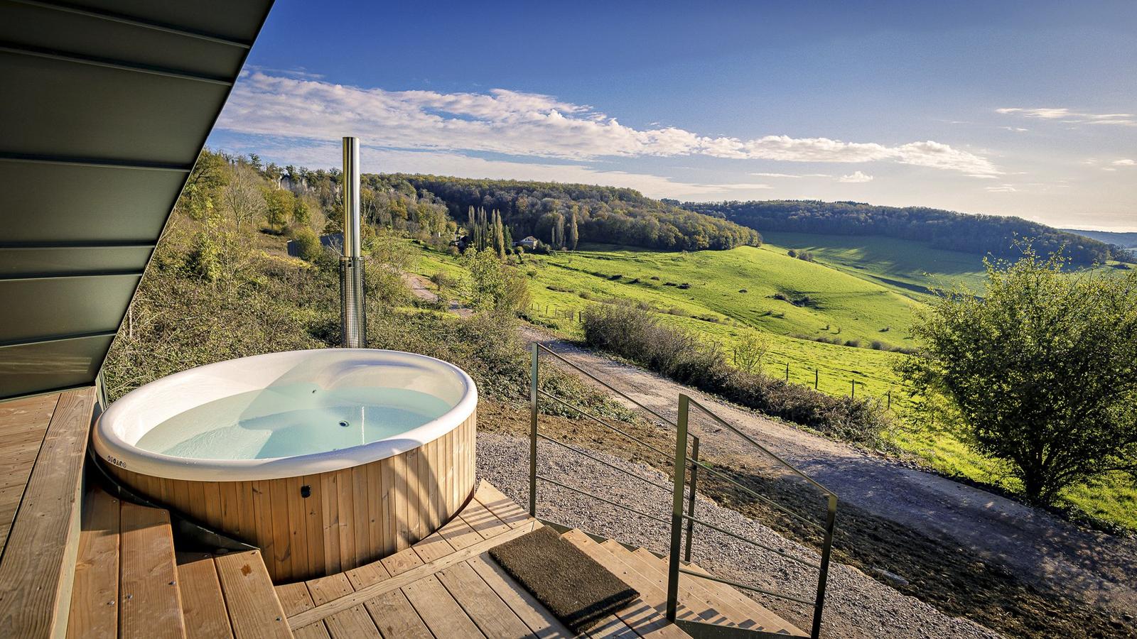 Le bain nordique en bois de Singi sur sa terrasse, face à la vallée verdoyante de l'Auxois