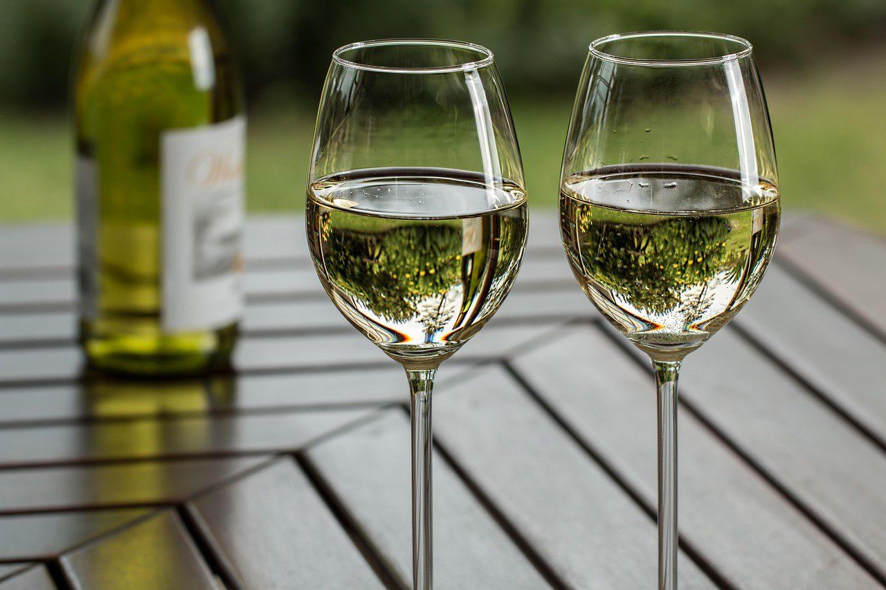 Deux verres de vin blanc et une bouteille sur une terrasse face à la campagne