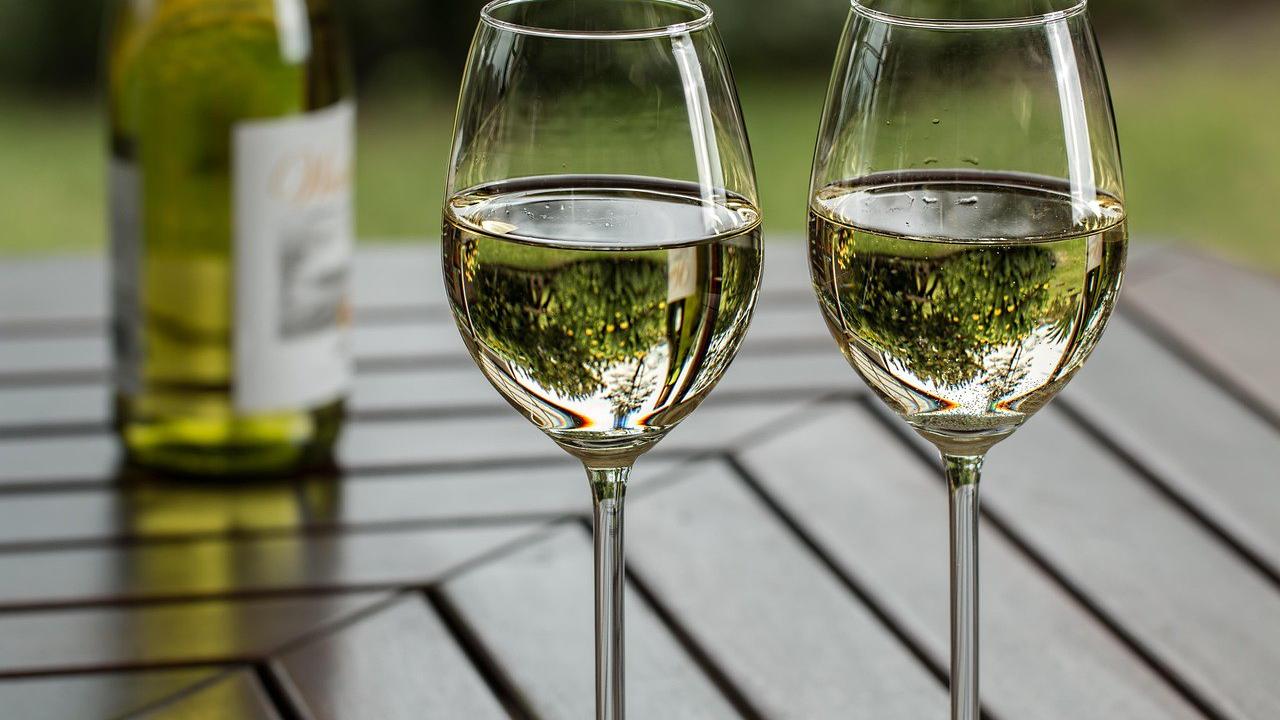 Deux verres de vin blanc et une bouteille sur une terrasse face à la campagne