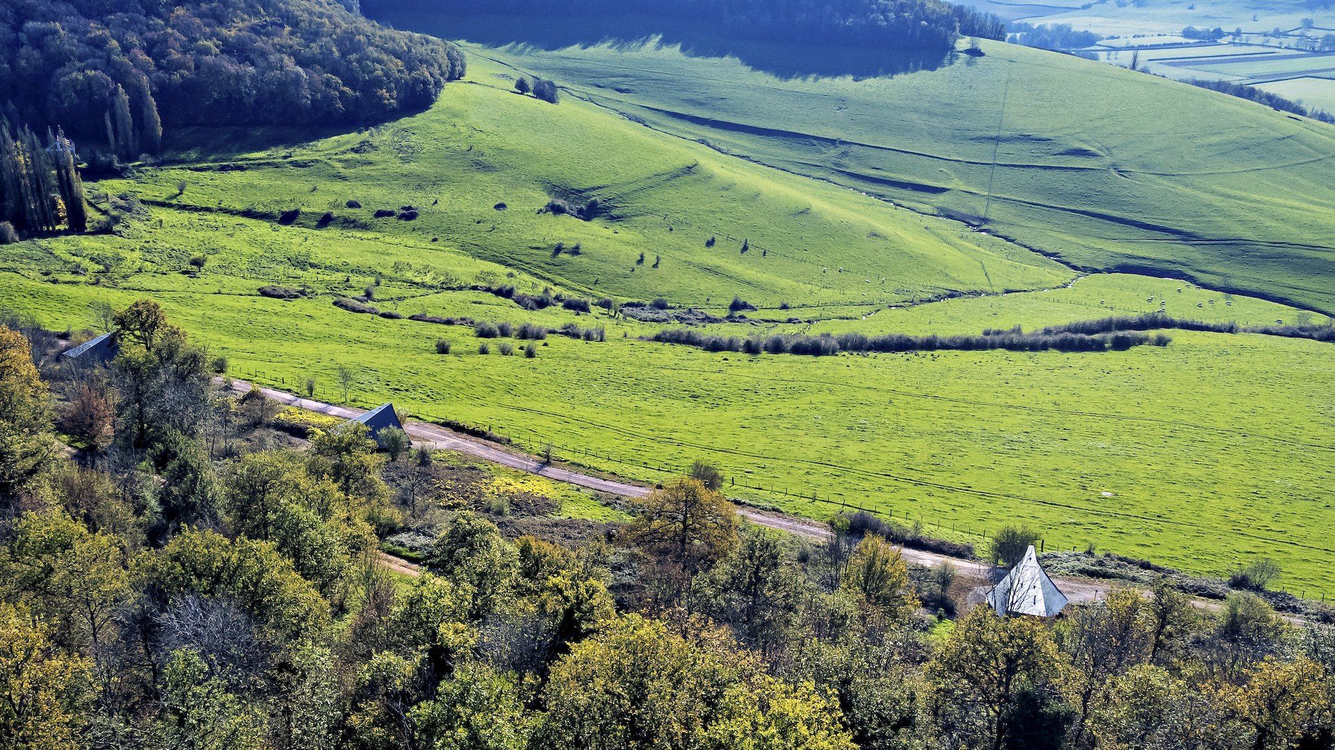 Vue d'en haut sur la vallée verte de l'Auxois, un lodge blanc au loin