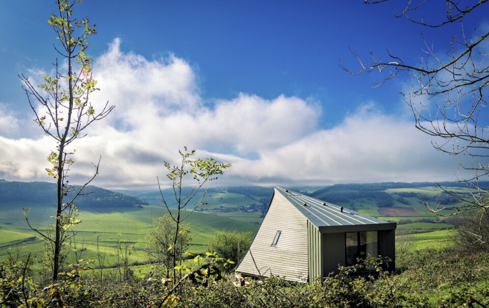 Maison moderne dans un paysage verdoyant.